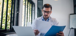 Physician working on laptop with documents