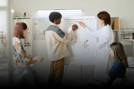 Academic researchers discussing research findings on a whiteboard