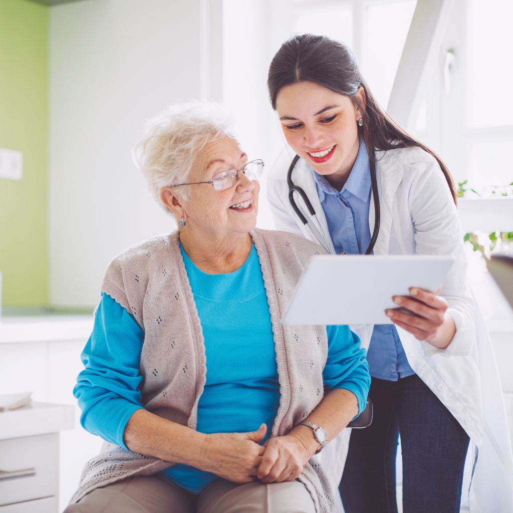 Female doctor helping an elderly patient view health information on a tablet