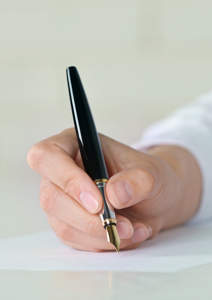 Hand holding fountain pen writing grant proposal