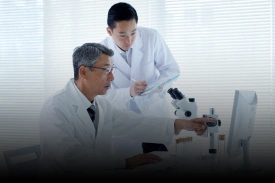 Researchers working with a microscope and scientific data